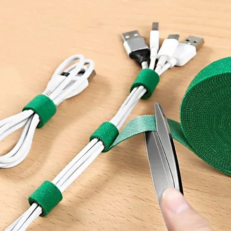 White cables with green ties on a wooden surface, with scissors cutting a green tie.